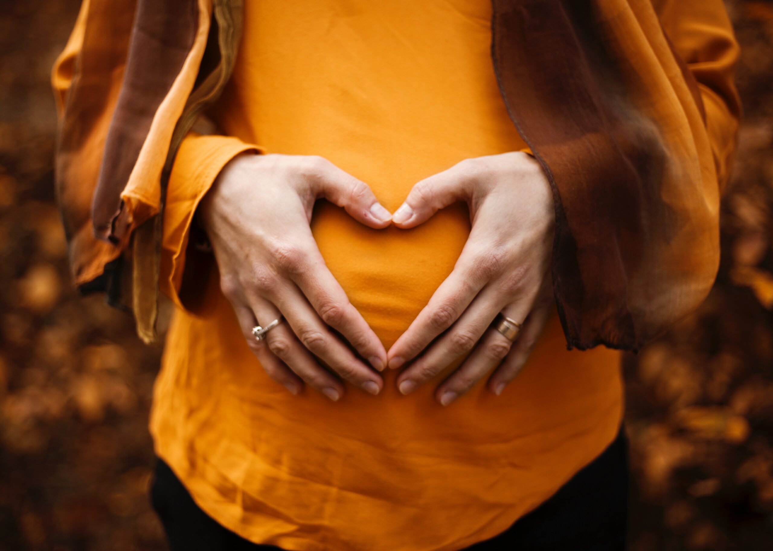 Schwangerer Bauch mit Herz von Händen geformt